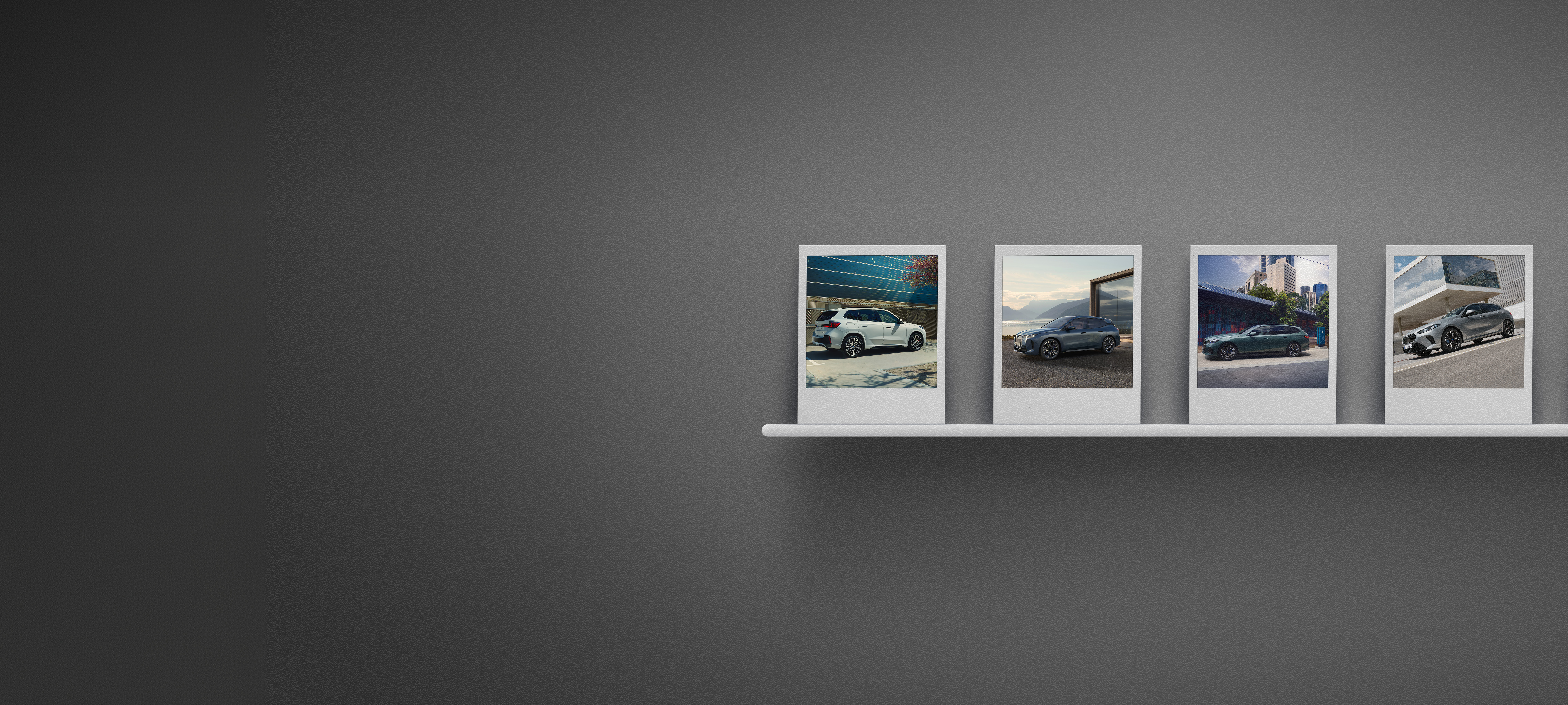 Das Bild zeigt eine dunkle, grau texturierte Wand, an der auf einer schmalen weißen Leiste vier Sofortbilder (Polaroids) aufgereiht sind, die verschiedene BMW-Modelle in unterschiedlichen Umgebungen zeigen.
