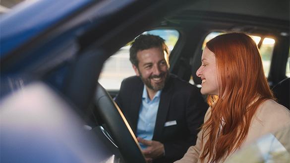 Probefahrt vereinbaren BMW Stadel Ein BMW Verkaufsberater und eine Kundin sitzen gemeinsam in einem blauen BMW.