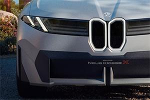 Eine Detailaufnahme der Fahrzeugfront. Man sieht die schmalen Scheinwerfer und die beleuchtete, vertikale BMW-Niere mit dem Schriftzug "Neue Klasse X" darunter.