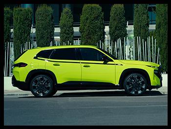 Die Profilaufnahme des BMW XM 50e betont die massive Präsenz des SUVs, die markante schwarze Akzentlinie entlang der Fenstergrafik und die exklusiven M-Leichtmetallräder.