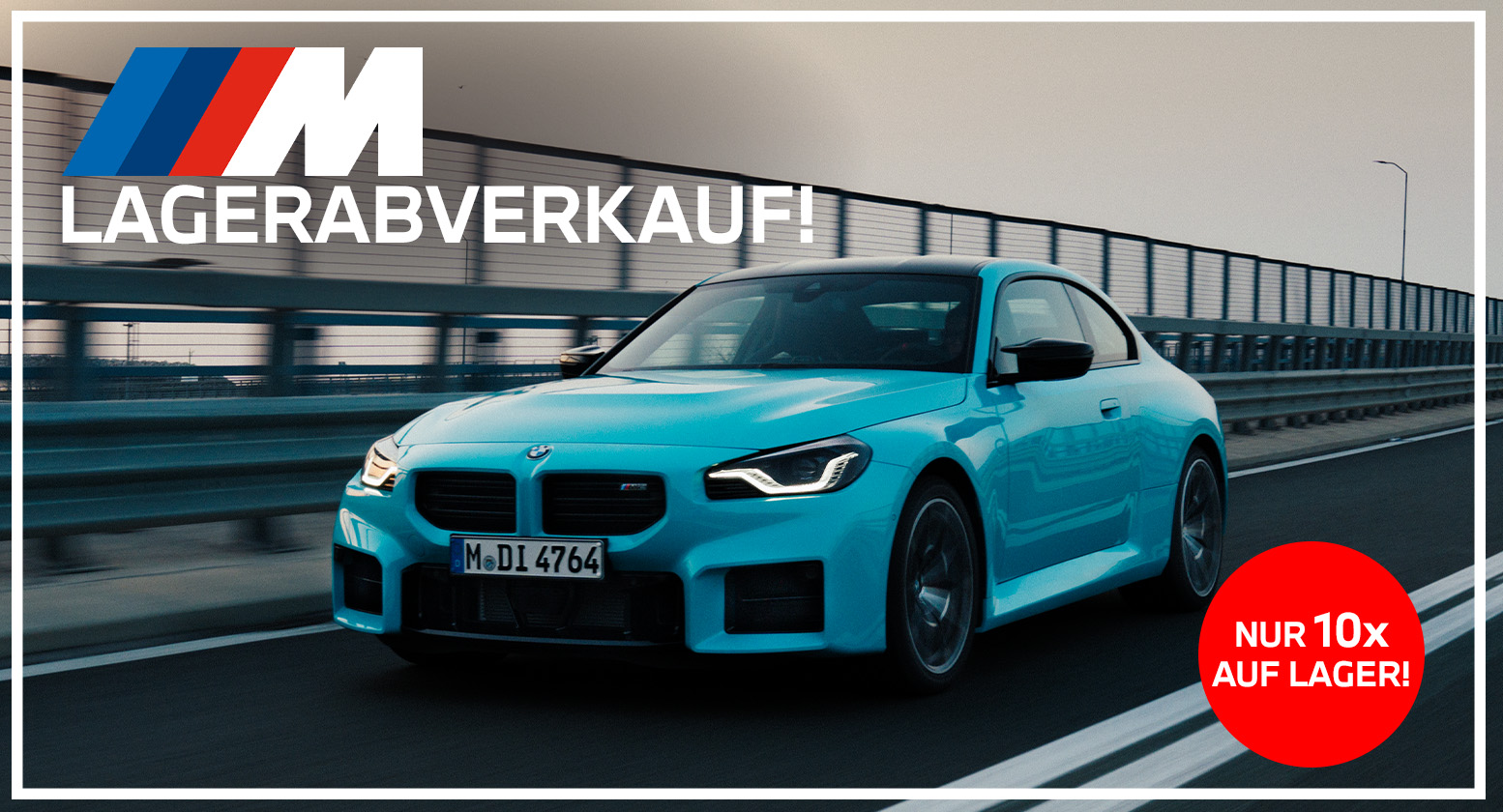 Werbebanner für einen BMW M Lagerabverkauf im Breitbildformat: Ein hellblauer BMW M2 fährt auf einer mehrspurigen Straße an einem langen Brückengeländer vorbei. Oben links ist das BMW M Logo mit dem Text „LAGERABVERKAUF!“ eingefügt, unten rechts signalisiert ein roter Kreis „NUR 10x AUF LAGER!“