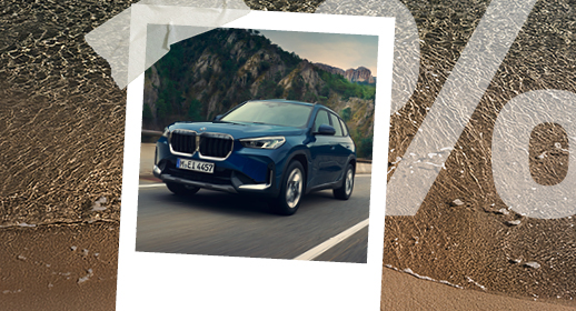 Ein Polaroid-Foto auf Strand-Hintergrund zeigt einen dunkelblauen BMW X1 vor einer Kulisse aus Felsen und Bäumen. Rechts ist wieder das große, transparente Prozentzeichen (%) zu sehen.