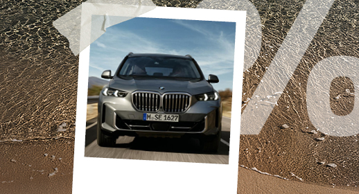 Ein Polaroid-Foto auf Strand-Hintergrund zeigt einen grauen BMW X5 von vorne auf einer Straße. Rechts ist wieder das große, transparente Prozentzeichen (%) zu sehen.